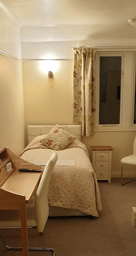 cozy bedroom with a single bed desk and chair warm lighting soft colored curtains and floral design suitable for six guests