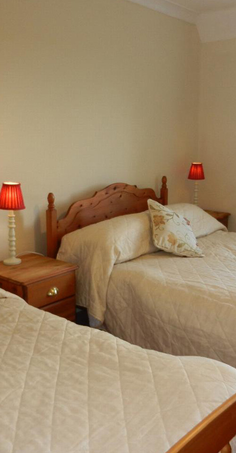 two beds in a cozy room with red lamps and a decorative pillow suitable for 21st century accommodation