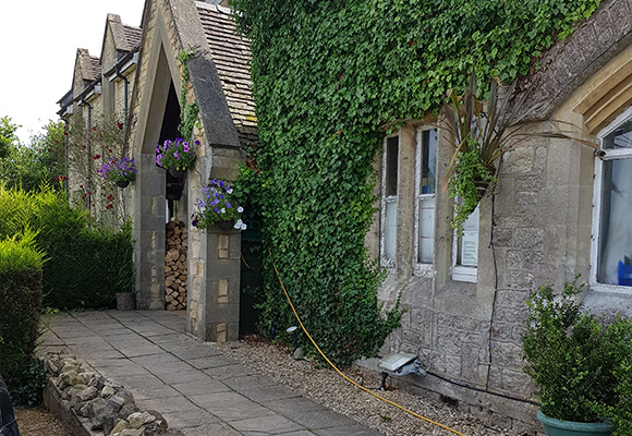 stone cottage with green ivy and colorful flowers along the pathway leading to the entrance surrounded by lush greenery and a rustic woodpile perfect for nine picturesque moments