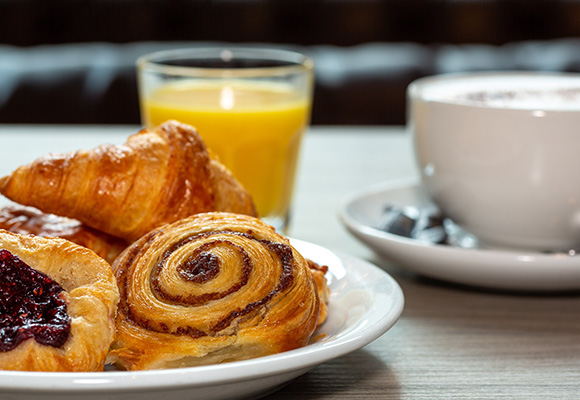 freshly baked pastries including croissants and cinnamon rolls served with a cup of coffee and orange juice perfect for a 15 minute breakfast break