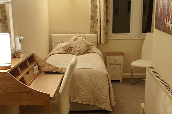 cozy bedroom with a single bed writing desk and chair curtains with floral pattern