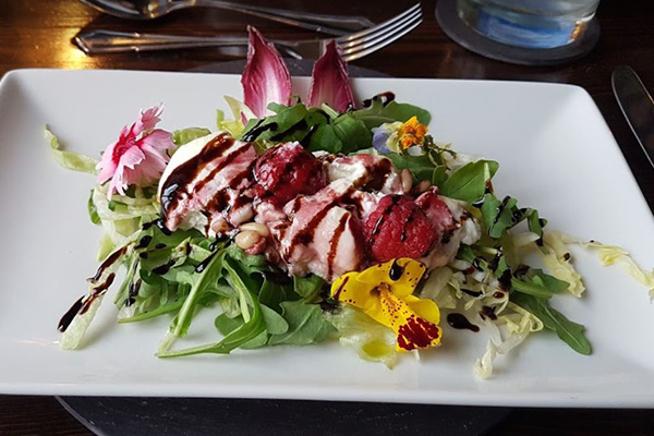 a vibrant salad featuring mixed greens topped with herbs edible flowers and a drizzle of balsamic vinegar showcasing eight colorful elements from the garden
