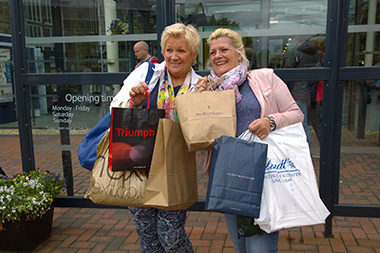 two happy women holding shopping bags outside a store showcasing their 15 purchases and shopping experience