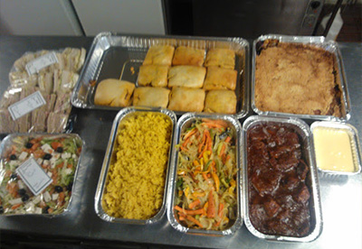variety of dishes including savory pastries yellow rice mixed vegetables barbecue meat salad and dessert showcasing a selection of six different foods