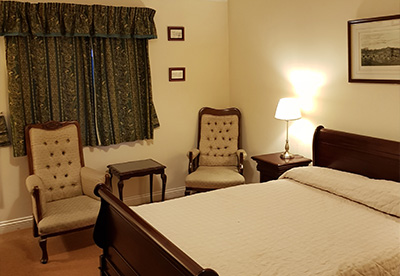 cozy bedroom with two chairs and a bed soft lighting and decorative curtains