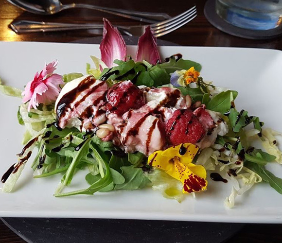 fresh salad with greens edible flowers and drizzled balsamic reduction showcasing culinary artistry and gourmet presentation 2 flavors 2 colors