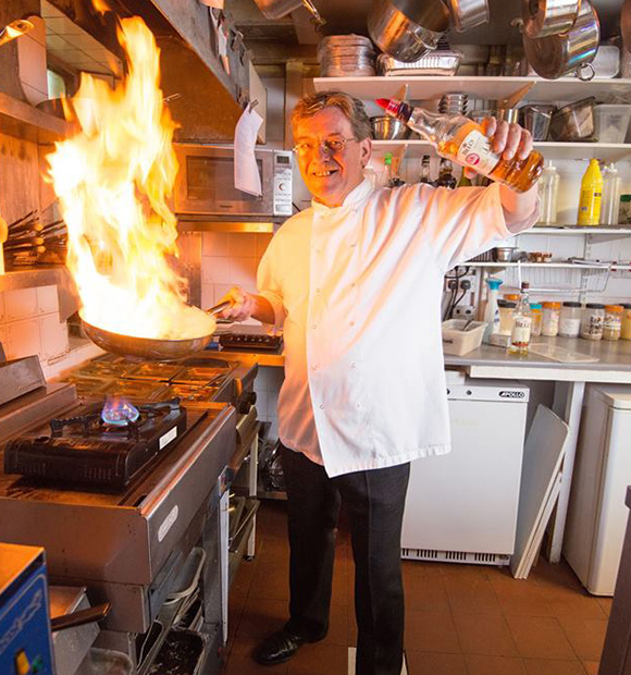 chef cooking with flame in busy kitchen preparing gourmet dish