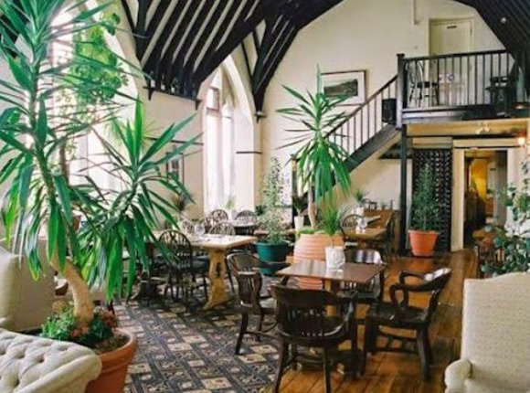 a cozy dining area with wooden furniture and indoor plants featuring a staircase and high ceilings for a relaxing atmosphere